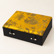 Geschlossene Schmuckkassette Gold, Klein, mit Blumen- und Pfauenmotiv sowie zwei Knebelverschlüssen.
